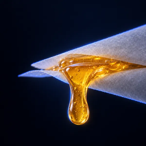 Druppel amberkleurige live rosin tussen twee vellen bakpapier
