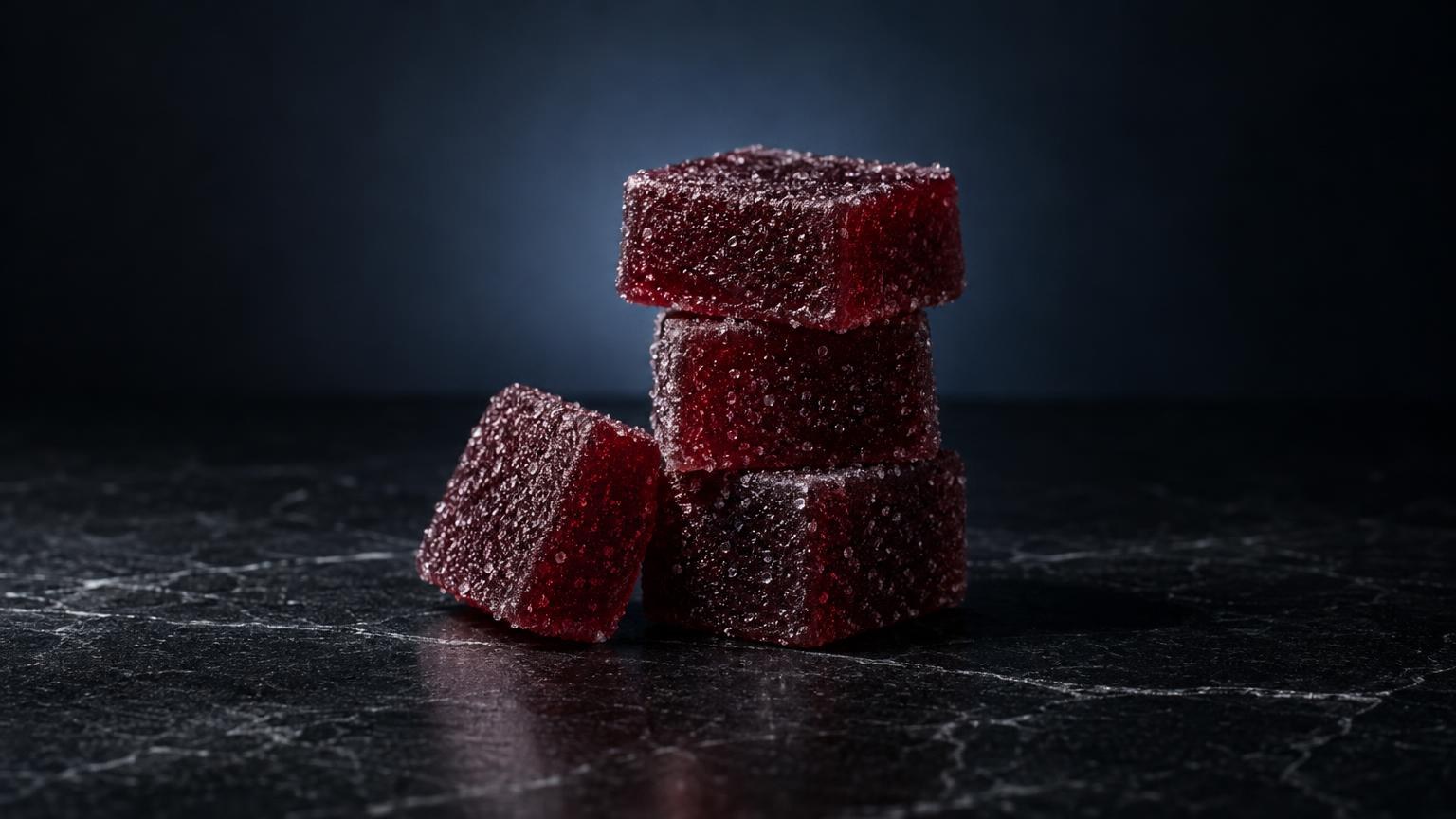Bon bon gummies: drie rode gummies met kristallijne suiker coating op donkere achtergrond, gestapeld en los