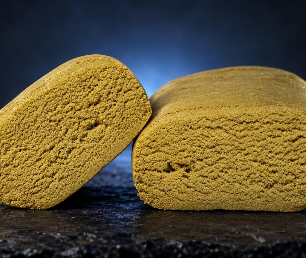 Twee gele, poederachtige blokken bubble hash met poreuze textuur op donkere ondergrond