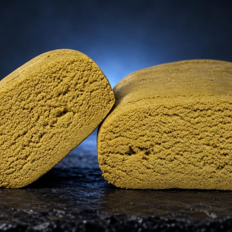 Twee gele, poederachtige blokken bubble hash met poreuze textuur op donkere ondergrond