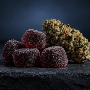 Rode CBD gummies met suikerlaag naast cannabisbloem op donker oppervlak, illustratie van productsoorten.