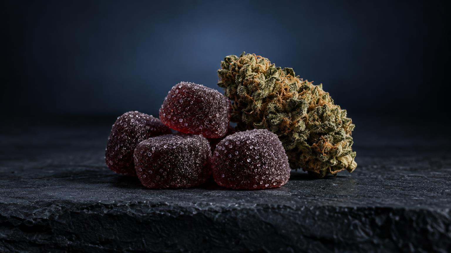 Rode CBD gummies met suikerlaag naast cannabisbloem op donker oppervlak, illustratie van productsoorten.