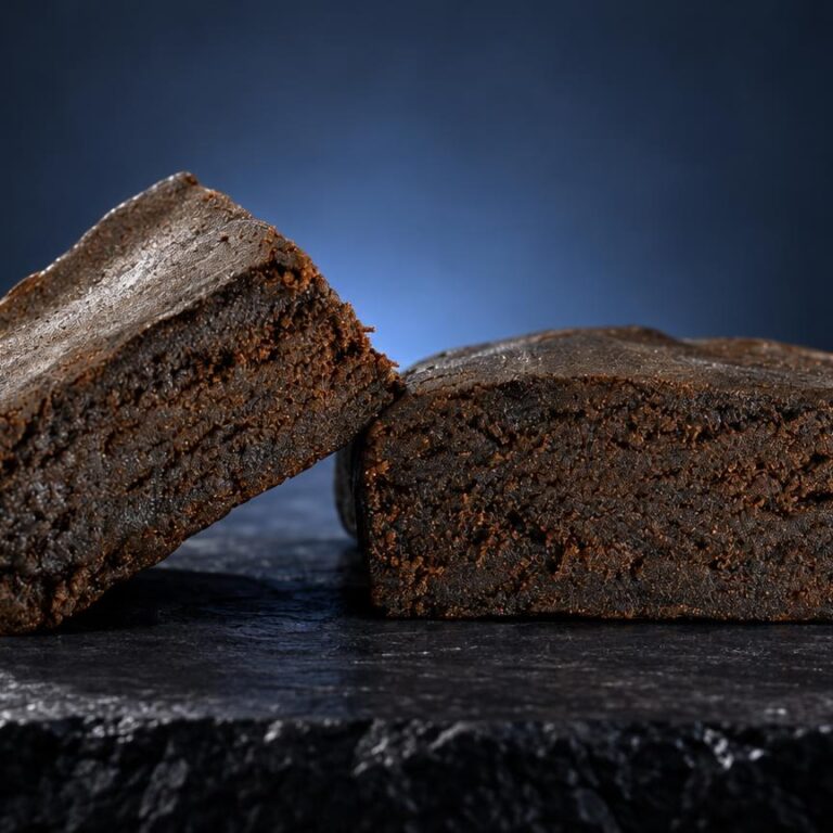 Twee bruine hashblokken met korrelstructuur op donkere ondergrond, illustrerend de traditionele vorm van dit product